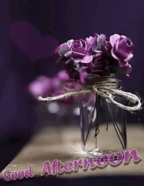 a vase filled with purple roses is on a table with the words `` good afternoon '' written on it .