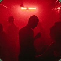 a man and woman are dancing in a dark room with red lights