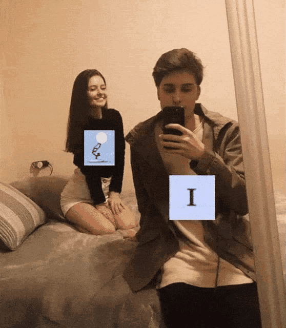 a man taking a selfie with a woman sitting on a bed behind him