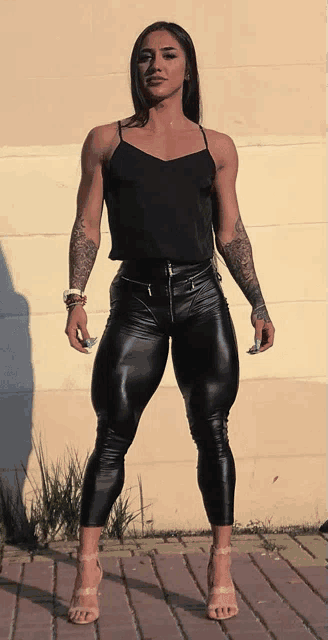 a woman in a black tank top and black leather pants