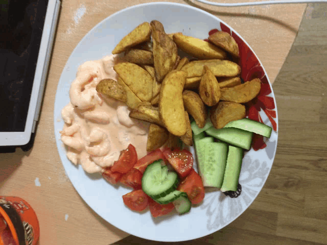 a plate with french fries tomatoes and cucumbers on a table