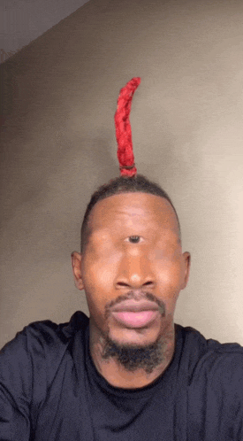 a man wearing a black shirt has a red item on his head