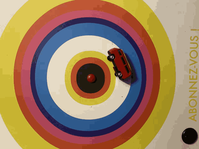 a red toy car is in the center of a rainbow colored circle