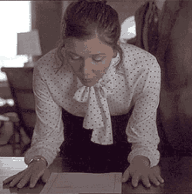 a woman in a polka dot shirt is kneeling down at a table