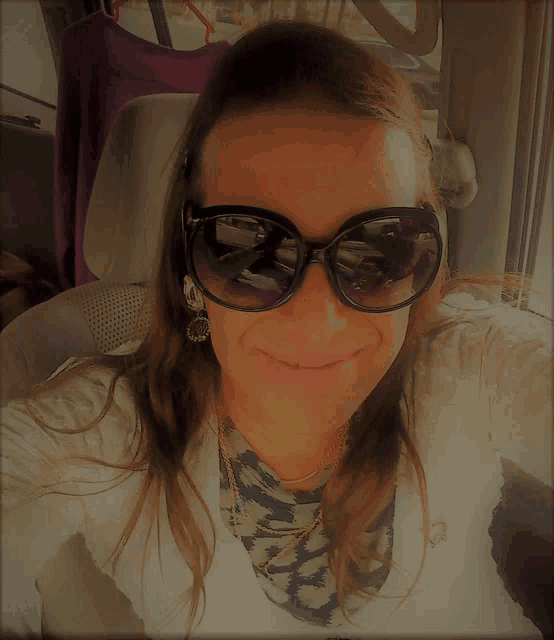 a woman wearing sunglasses and earrings is smiling in a car