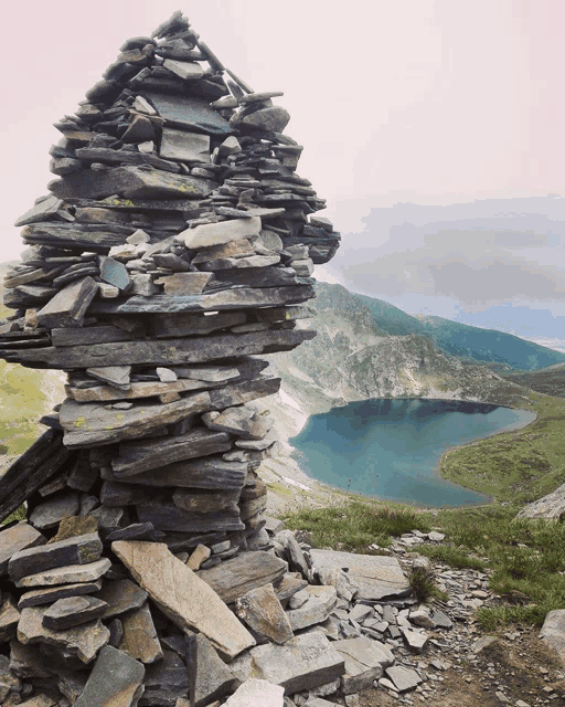 a pile of rocks sits in front of a lake