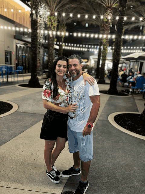 a man and a woman are posing for a picture and the woman is wearing a shirt that says ' hawaii '