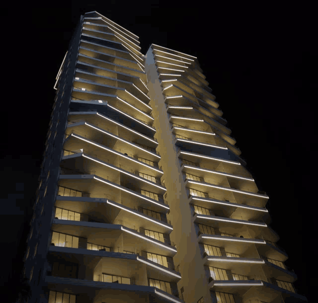 a very tall building with a lot of windows and balconies lit up at night