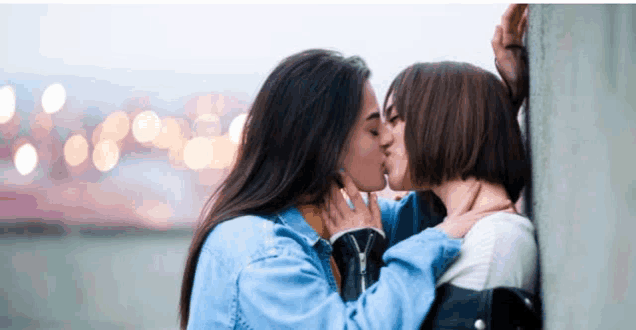 a couple of women kissing each other on a wall .