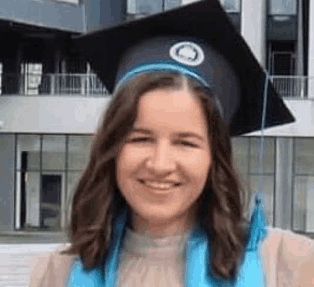 a woman wearing a graduation cap and gown is smiling and standing in front of a building .