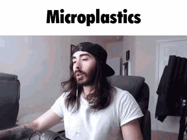 a man with long hair and a hat is sitting in front of a computer with the words microplastics written above him