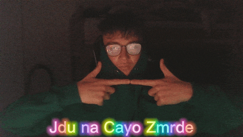 a person wearing glasses and a green hoodie with jdu na cayo zmrde written on the bottom