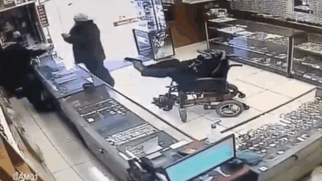 a man in a wheelchair is being attacked by a man in a gun .