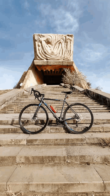 a bicycle is parked on a set of stairs in front of a statue that says " obelisco "