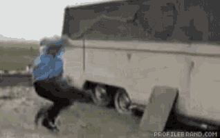 a man in a blue jacket is jumping in front of a trailer ..