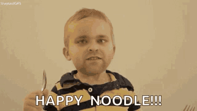 a little boy is holding a fork and eating noodles .