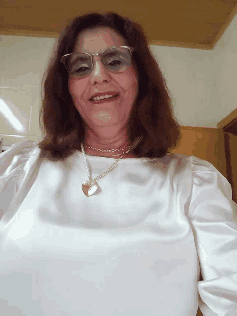 a woman wearing glasses and a necklace with a heart on it