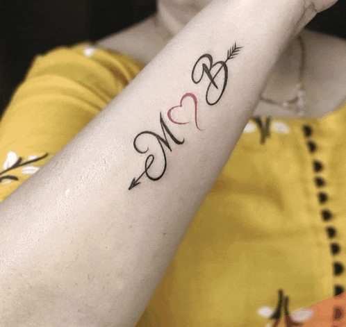 a woman has a tattoo on her forearm with the initials m and b