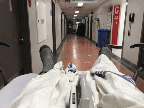 a person laying on a stretcher in a hospital hallway with a sign that says emergency