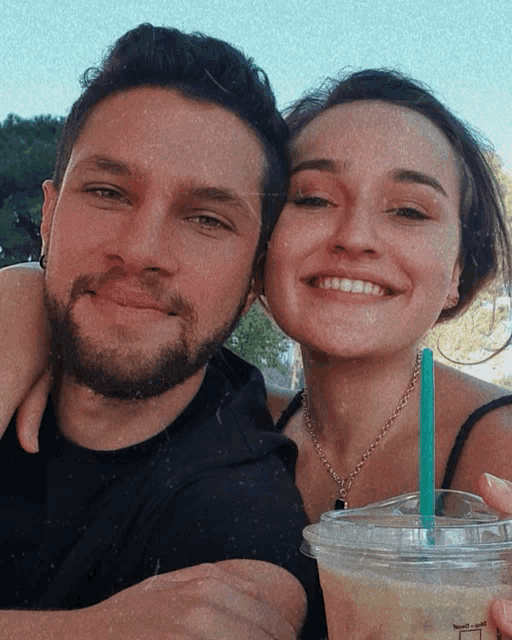 a man and a woman are posing for a picture with a starbucks drink