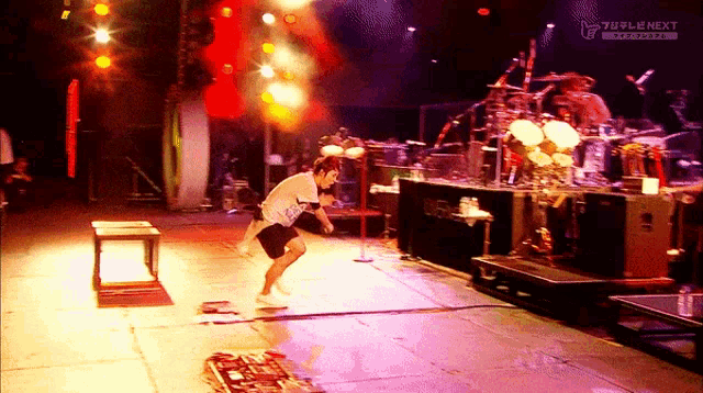 a man stands on a stage in front of a drum set and a sign that says ' next ' on it