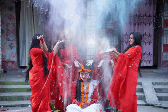 a group of women in red dresses are standing around a bride