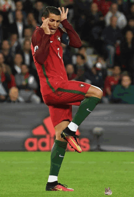 a soccer player with the number 1 on his jersey stands on one leg