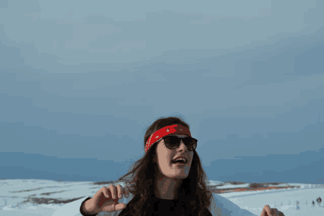 a woman wearing sunglasses and a red bandana is standing in the snow