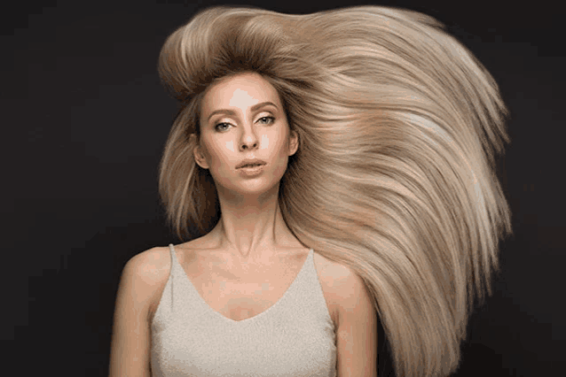 a woman with long blonde hair looks at the camera