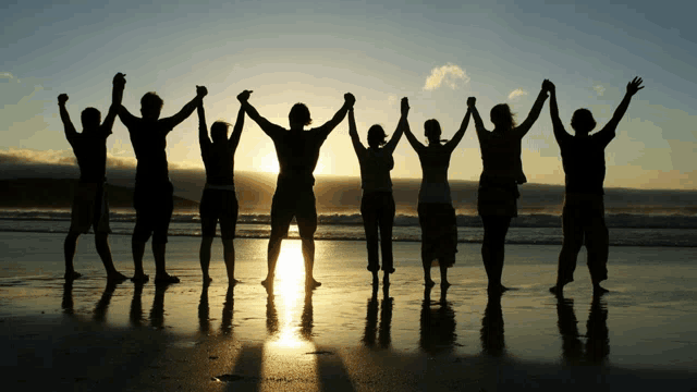 a group of people standing on the beach holding hands