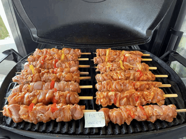 chicken skewers are being cooked on a grill with a note that says " for sale "