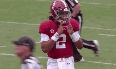 a football player wearing a red jersey with the number 2 on it is making a heart with his hands .