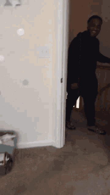 a man in a black hoodie stands in a hallway