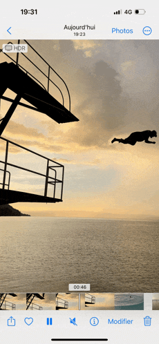 a phone screen shows a picture of a man jumping into the ocean