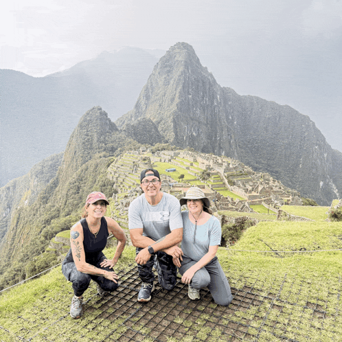 a man and two women pose for a photo in front of a mountain