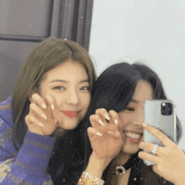 two women are taking a picture of themselves with their phones