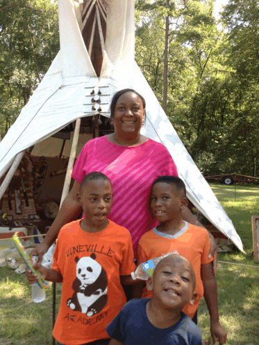 a woman stands next to two young boys wearing orange shirts that say kineville academy