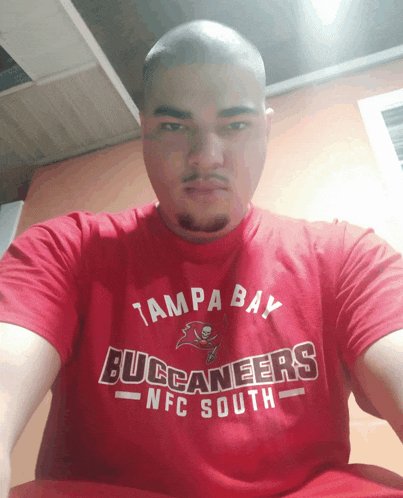 a man wearing a red tampa bay buccaneers nfc south t-shirt