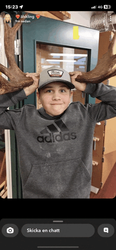 a young boy wearing an adidas sweatshirt is holding antlers over his head