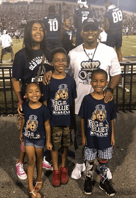 a man and three children wearing big blue kids club shirts