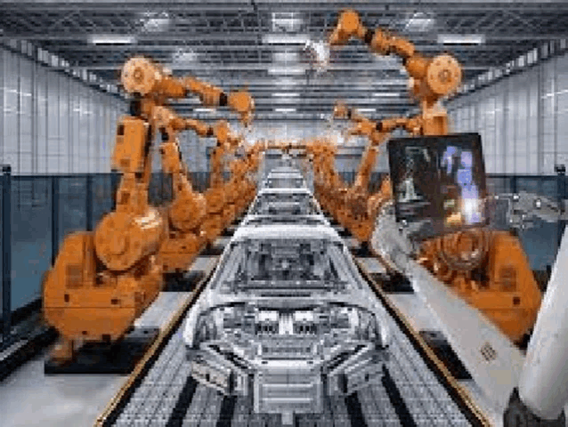 a robotic arm is holding a tablet while a car is being assembled in a factory .