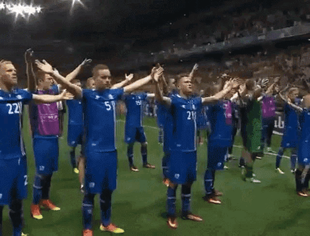 a group of soccer players are standing on a field with their arms outstretched and one has the number 21 on his shirt