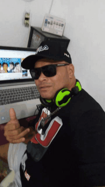 a man wearing headphones and a fila hat is giving a thumbs up