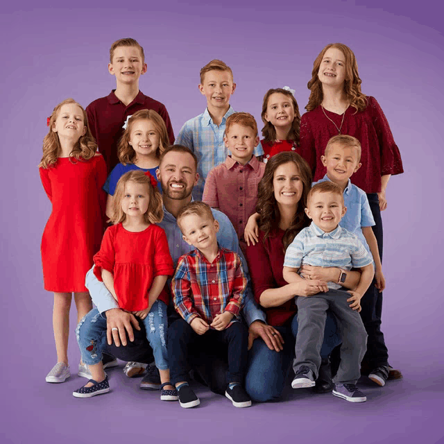 a large family posing for a picture against a purple background