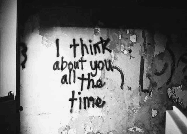 a black and white photo of a graffiti message on a wall that says `` i think about you all the time '' .