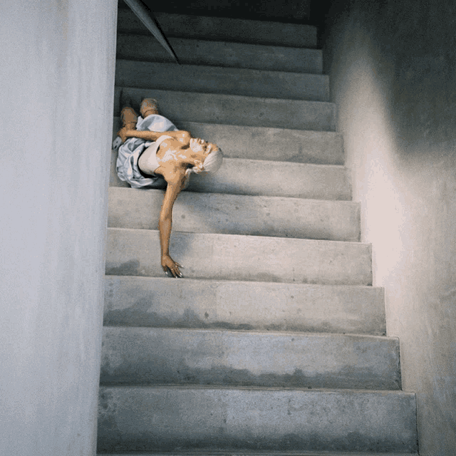 a woman is laying on a set of stairs with her head down