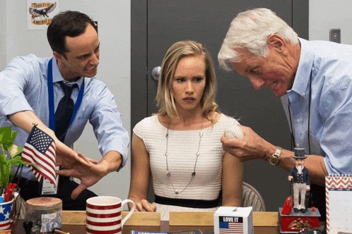 a woman sitting at a desk with two men and a box that says love it