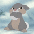 a cartoon rabbit with a mustache is sitting in the snow and looking at the camera .