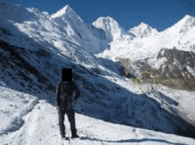 a person standing on top of a snow covered mountain looking at the mountains