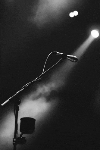 a black and white photo of a microphone in front of a spotlight